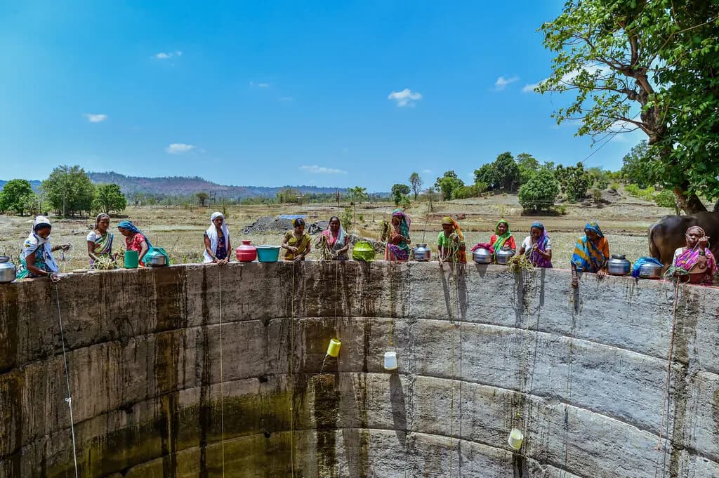 Rural women in India filling water from a well.