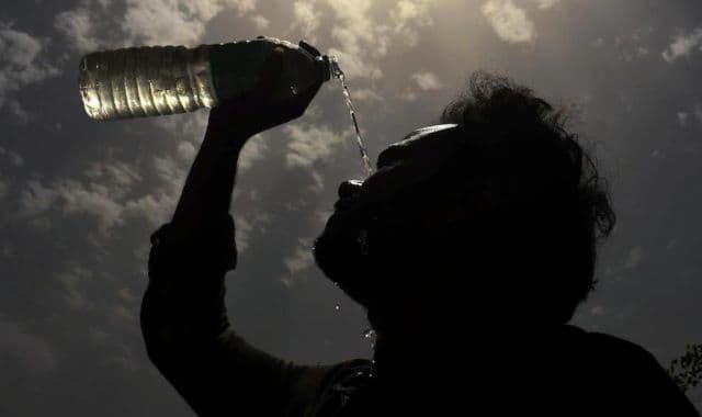 Man pouring water on his face on a hot summer day.