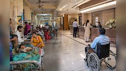 Patients wait amid overcrowded conditions inside a public hospital, reflecting the uneven burden of healthcare access and treatment costs in India.